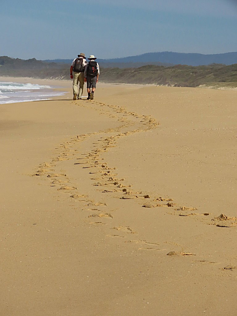 2 hikers walking along a beach south of Mystery Bay